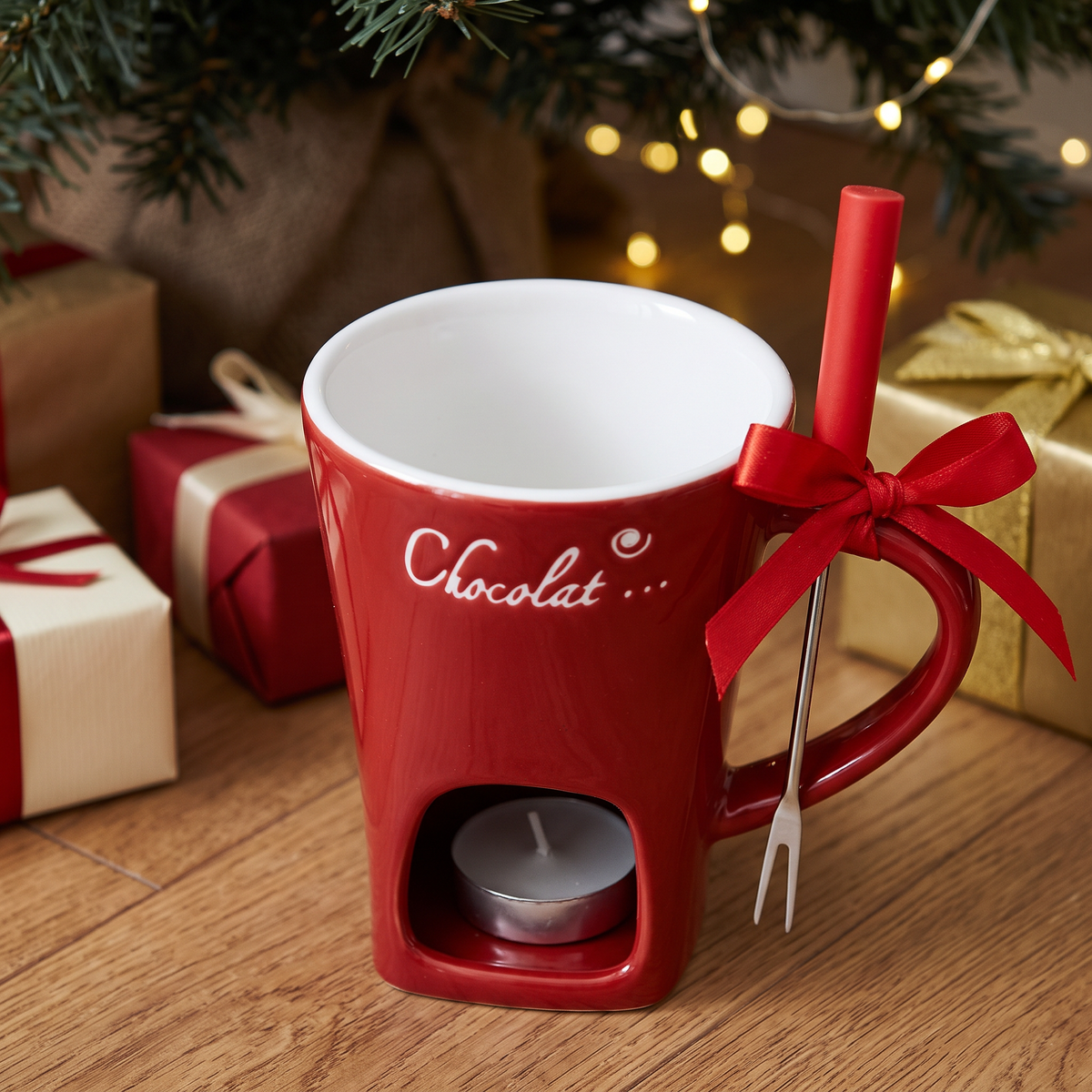Mini-Fondue-Tasse mit roter Schleife als Geschenk unter dem Weihnachtsbaum