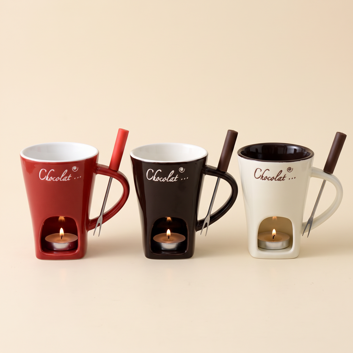 Mini-Fondue-Tassen in den drei Farben Rot, Schokobraun und Beige nebeneinander, jeweils mit Fondue-Gabel und brennendem Teelicht